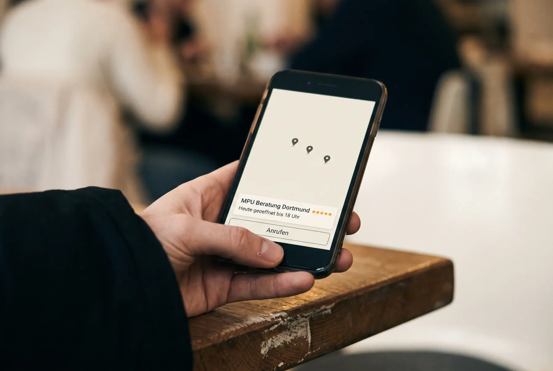 Ein Telefon zeigt eine Karte mit drei Nadeln, darunter ein Eintrag: „MPU Beratung Dortmund“, fuenf Sterne und ein Knopf „Anrufen“.